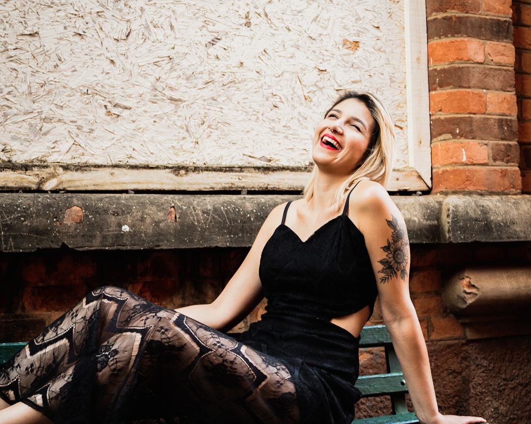 woman wearing black spaghetti-strap dress sitting on ground