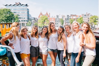 A group of women smiling warmly while walking together in a sunlit urban park.
