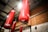 The image depicts several red punching bags hanging from the ceiling of a gym. The bags are branded with the name Challenger. They are suspended from black metal frames, and the gym walls are made of brick and painted white.