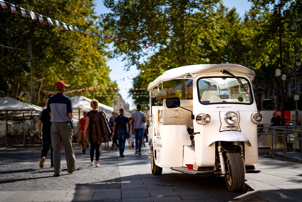 Rickshaw blanco estacionado cerca de un árbol