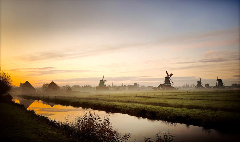 Poldermolens in de mist bij het ochtendgloren