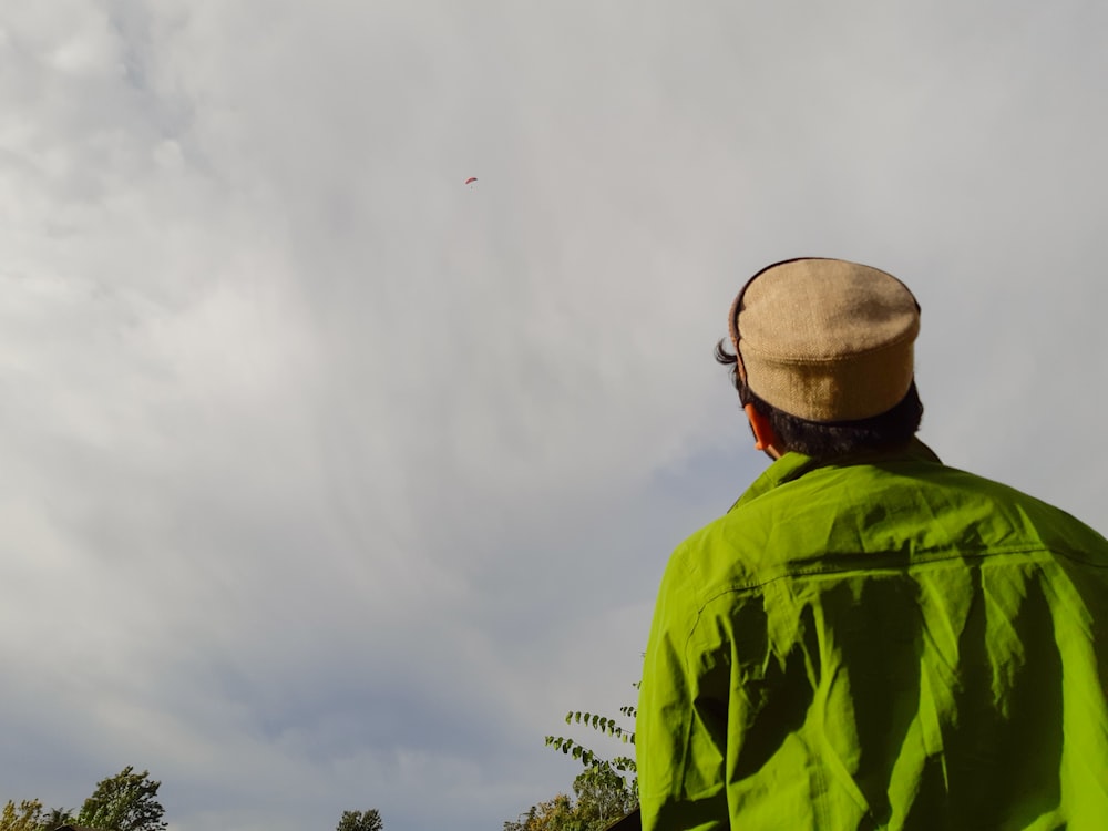 man wearing green jacket looking at sky