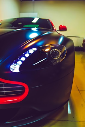 Close-up shot of a matte black custom car body kit with sharp red accents glowing under low light.