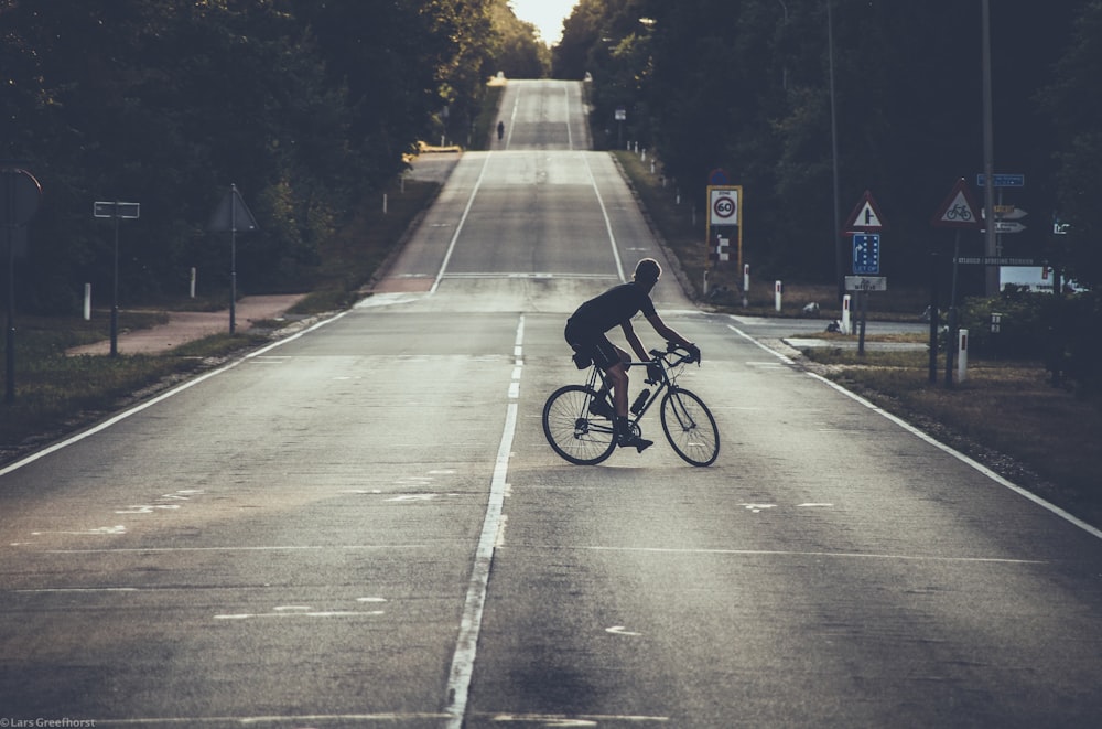 photography of person riding bicycle on road during daytime