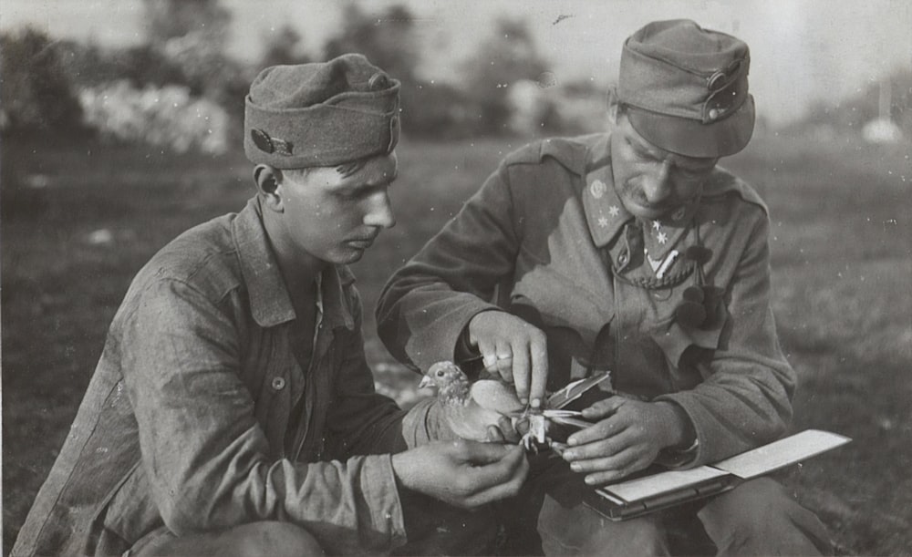 grayscale photo of man in jacket and cap holding smartphone