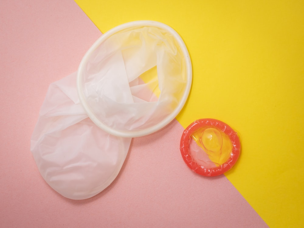 rotes Kondom auf rosa und gelber Oberfläche