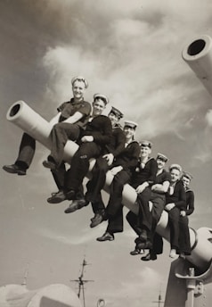 A group of diverse seafarers in uniform smiling confidently on the ship's bridge.