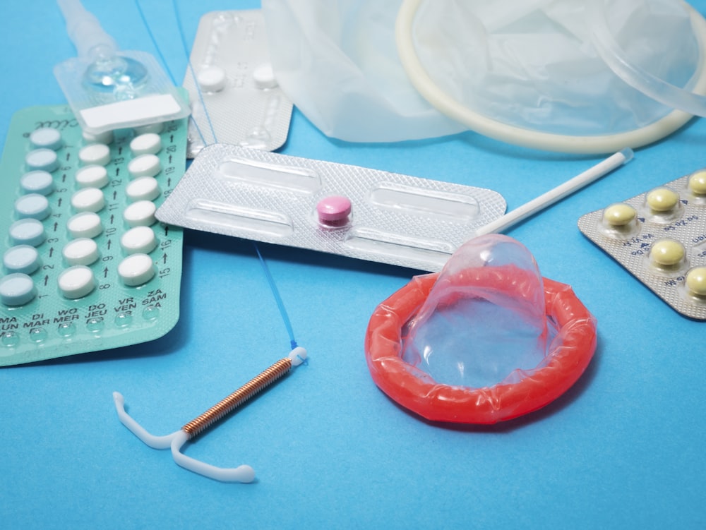 A variety of contraceptives: condoms, birth control pills, intrauterine device, and arm implant.