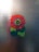 A colorful flower design, composed of multiple layers of petals in shades of red, pink, orange, green, and blue, is set against a textured, frosted glass background.