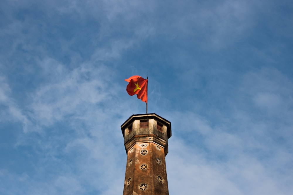 low-angle photography of red flag on top of a tower