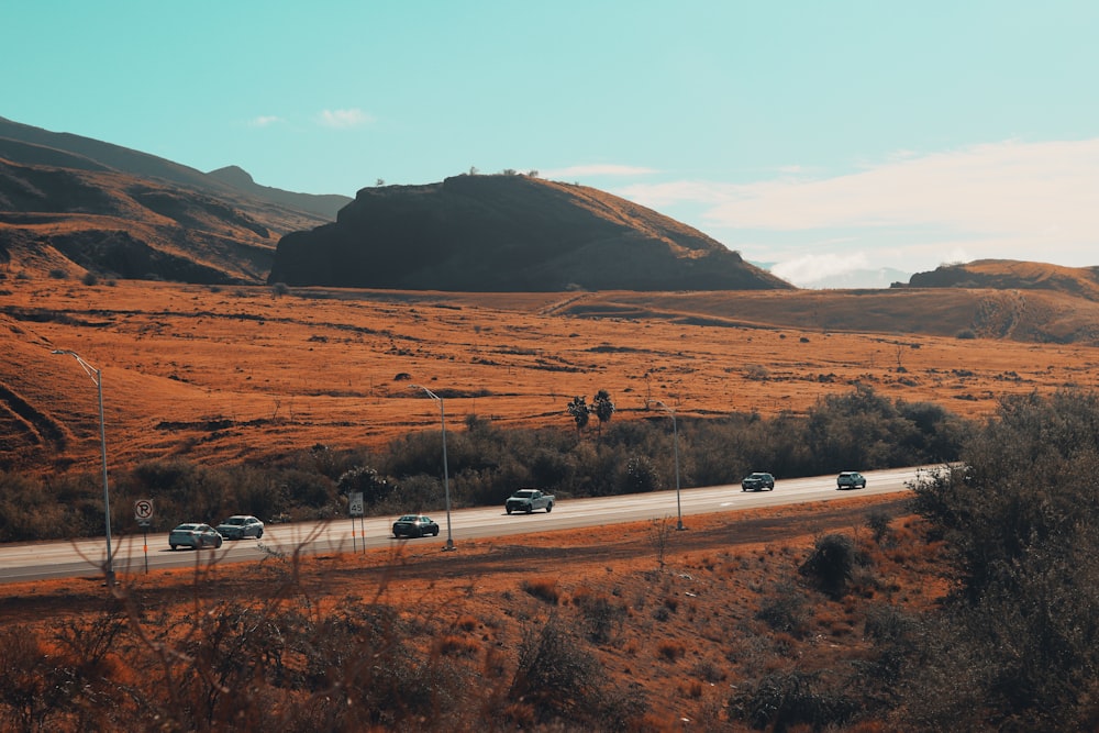 a group of cars driving down a road in the desert