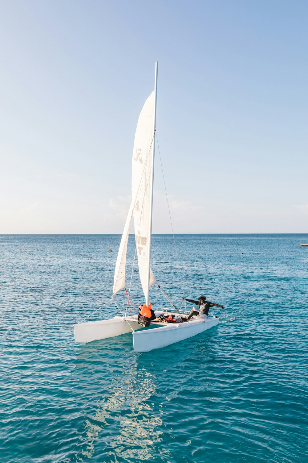 a sailboat with two people on it in the water
