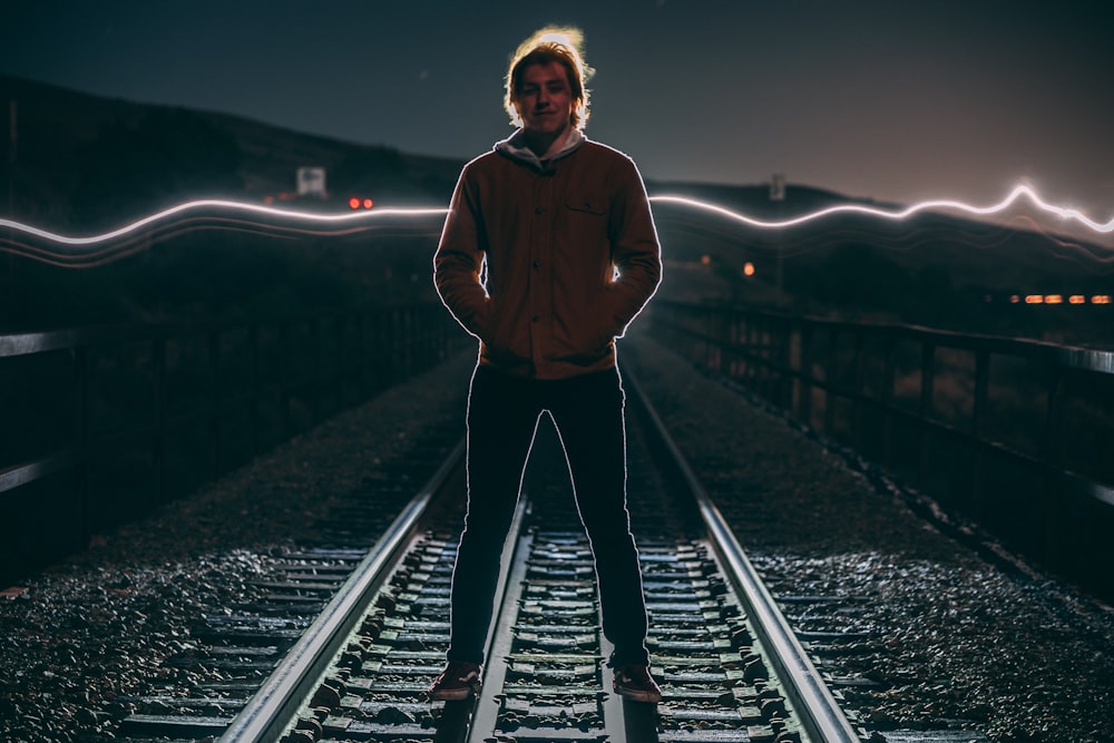 a man standing on a train track at night