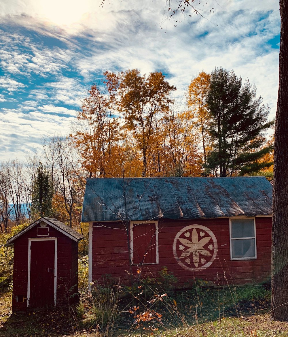 red wooden house and shed near trees under blue cloudy sky