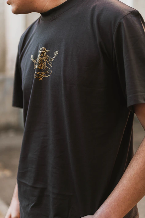 A close-up of a luxurious midnight black t-shirt adorned with a finely detailed copper Murugan emblem.