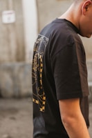 Model wearing a dark graphic tee with a modern Christian symbol on an urban street background.