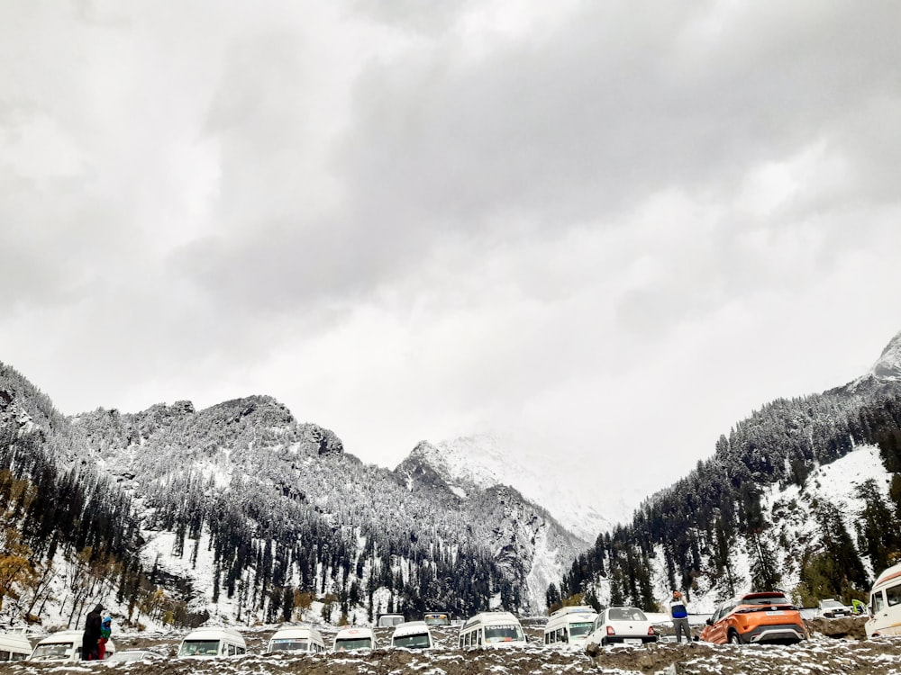 a group of cars parked in front of snow covered mountains