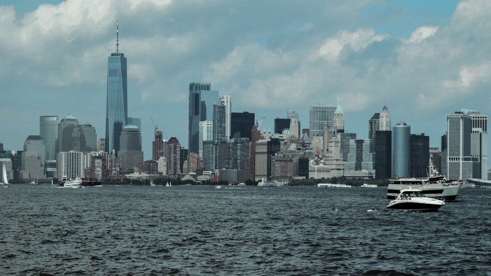 white and black yachts on body of water viewing New York City under blue and white sky