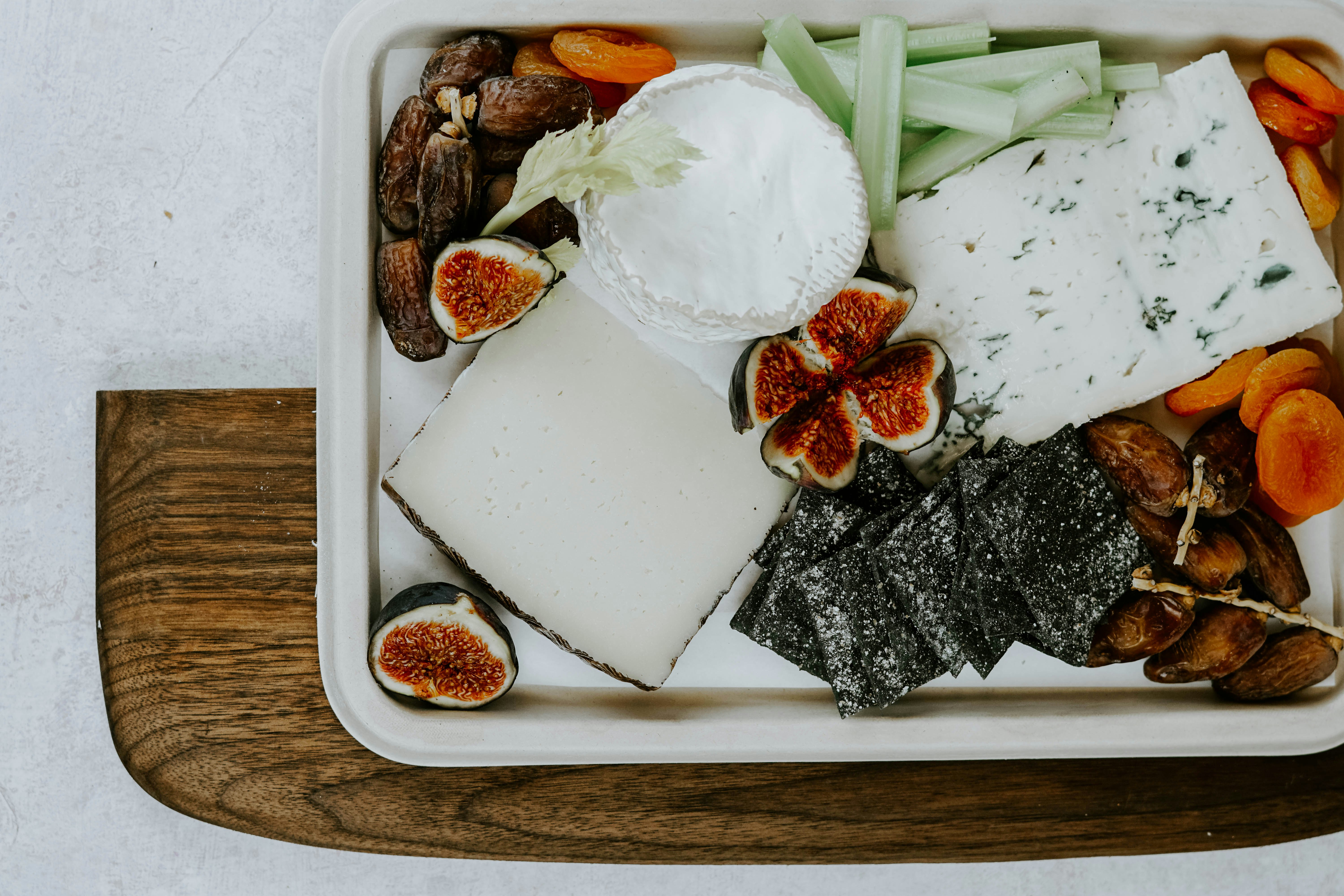 sliced fig fruit, white cheese, nuts, and yogurt on tray