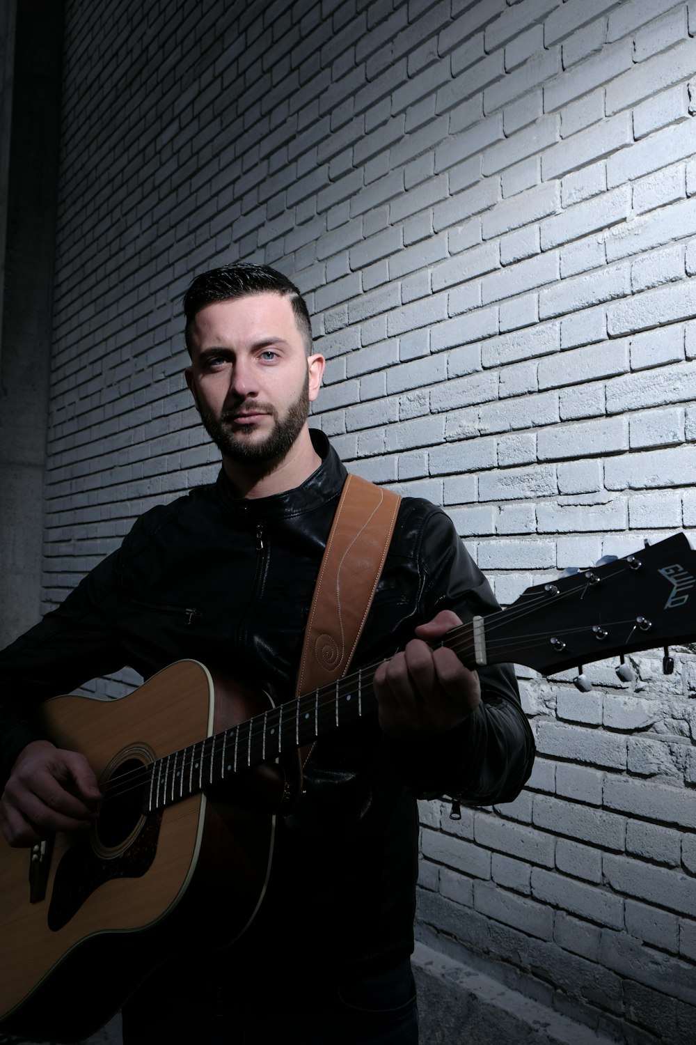 man carrying brown acoustic guitar