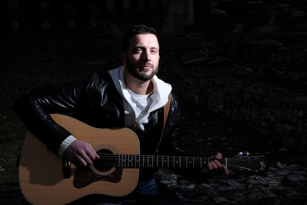 a man holding a guitar in a dark room