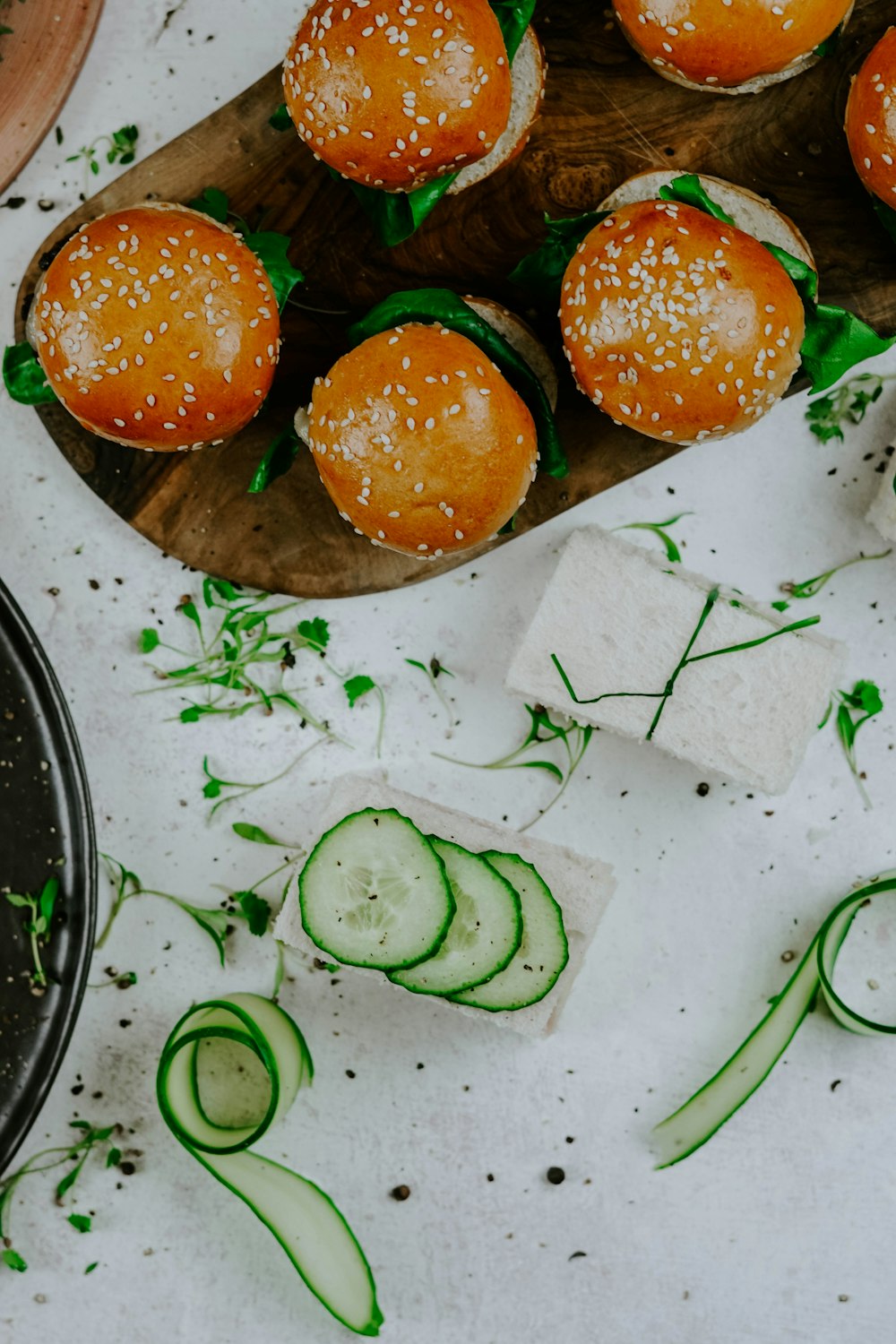 burgers on wooden surface near cucumber slices
