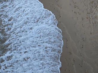 Waves gently crashing on the sandy shore of Ipanema with footprints leading to the water