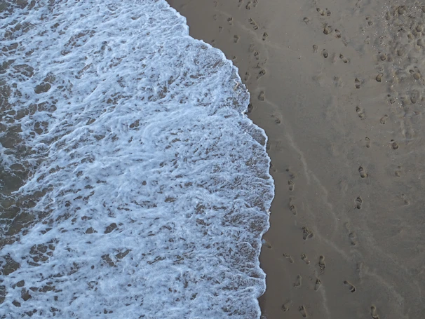 Waves gently crashing on the sandy shore of Ipanema with footprints leading to the water