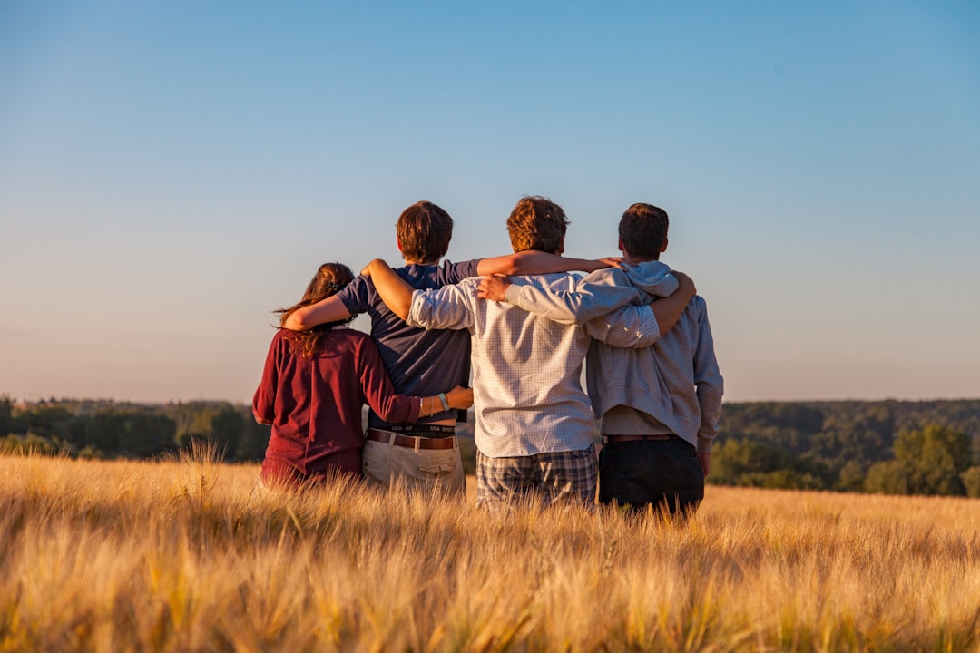 Four people enjoying a group hug in a field.