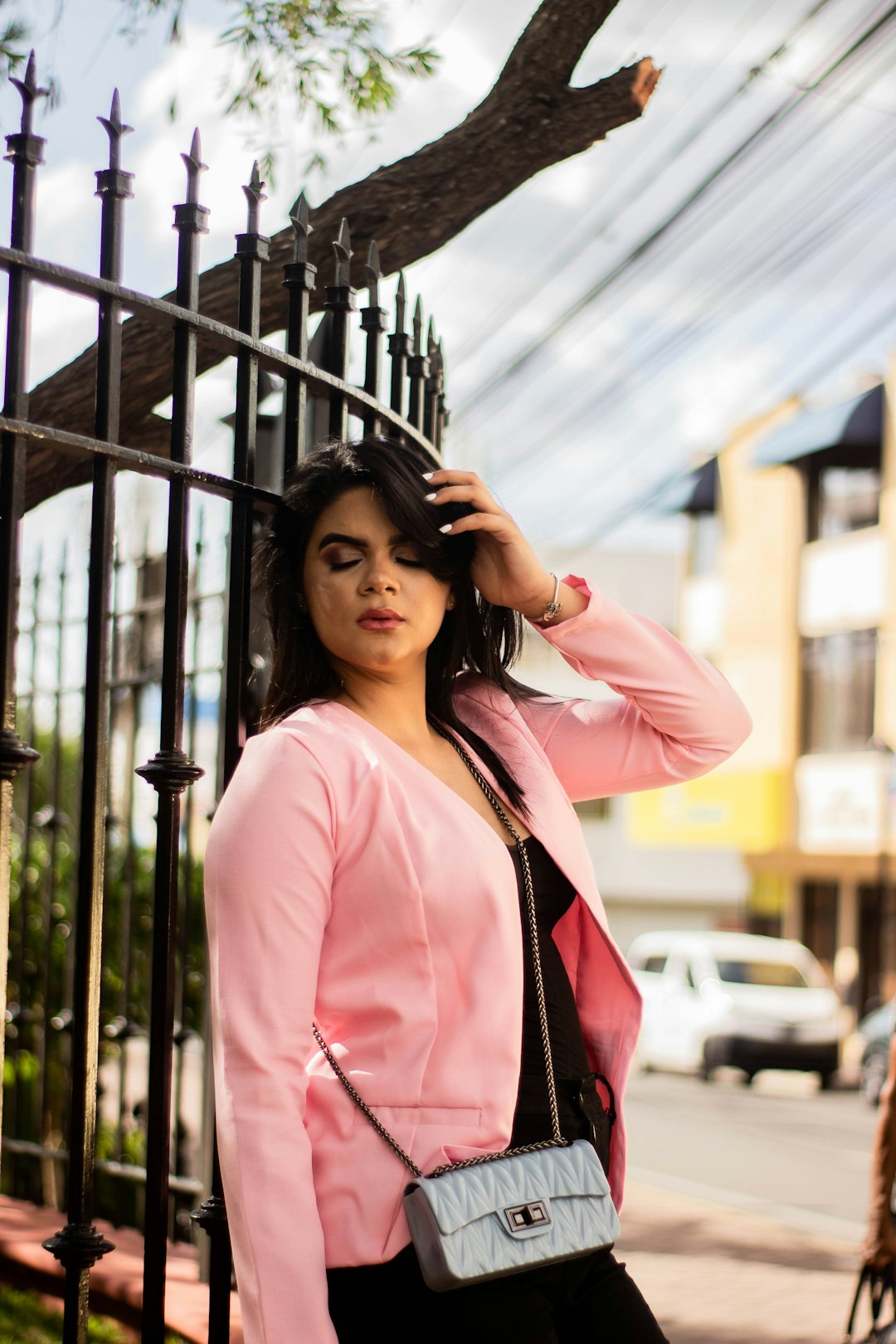 woman in pink jacket leaning beside metal fencce