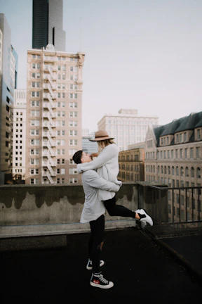 Couple embracing on a New York rooftop wearing matching romantic outing attire.
