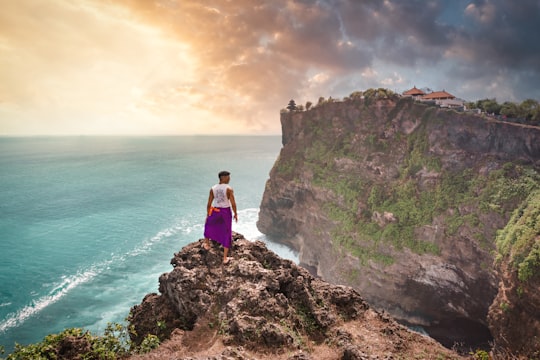 person standing on cliff in front of ocean during daytime in Uluwatu Temple Indonesia