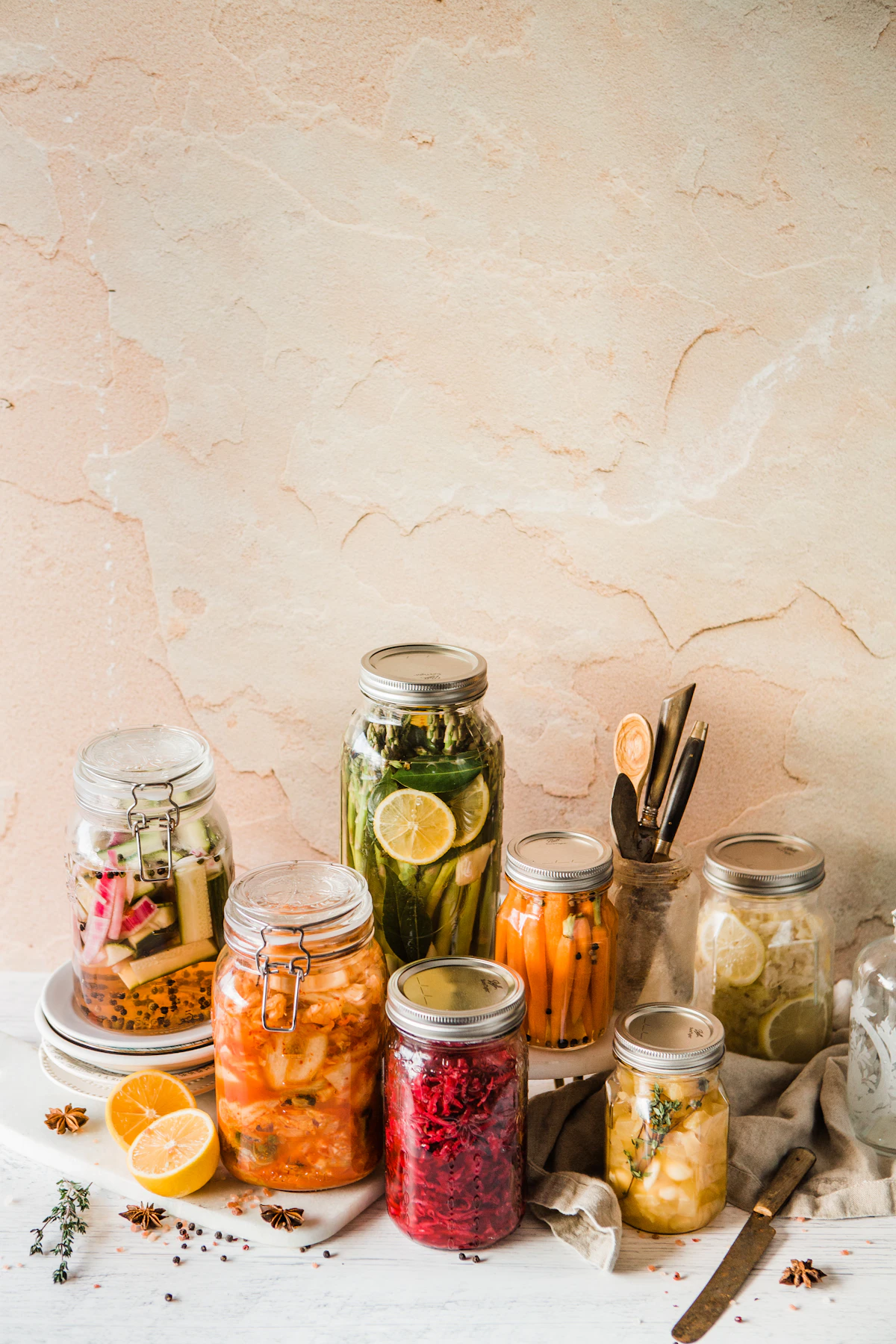 An assortment of glass jars filled with fermented vegetables — sauerkraut, pickles, and kimchi — on a kitchen shelf