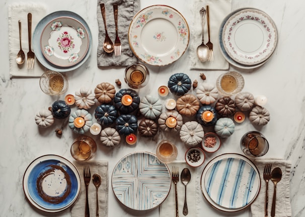 A cozy autumn table setup featuring warm-toned placemats and elegant ceramic dishes.