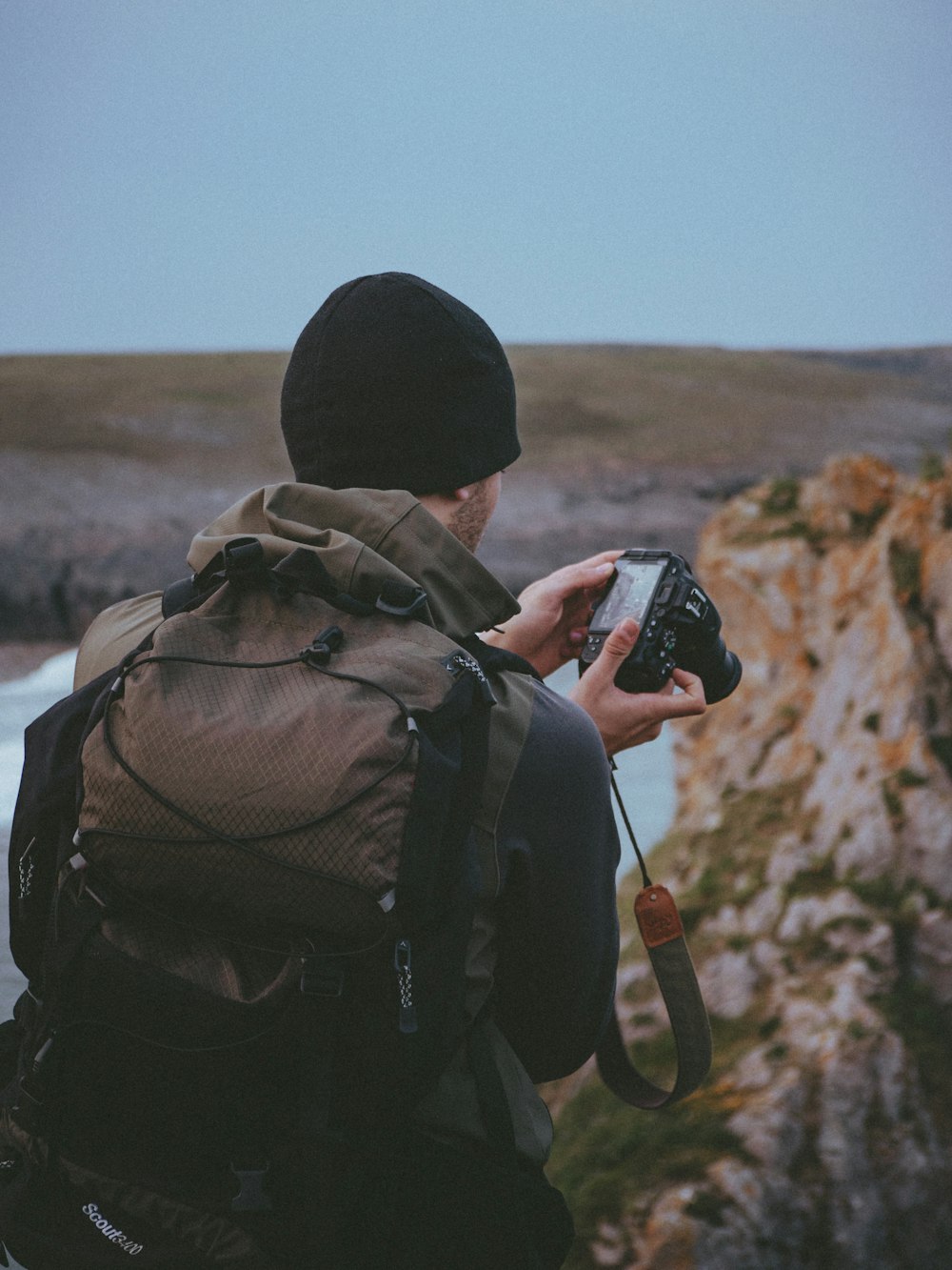 shallow focus photo of person wearing black knit cap using DSLR camera