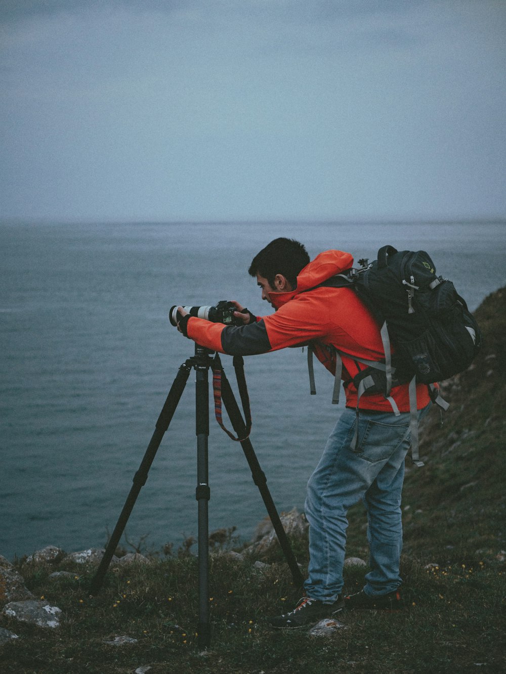 shallow focus photo of man in red hoodie using DSLR camera