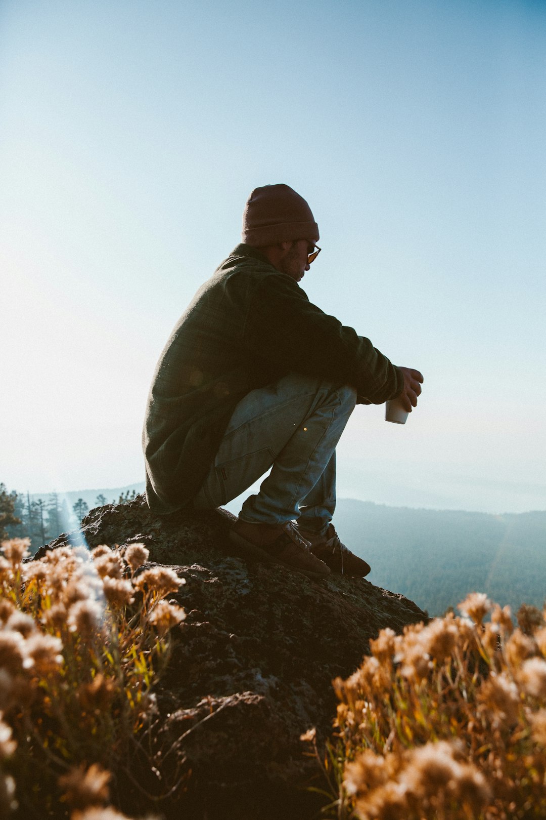 photography of man sits on rock formation near outdoor during daytime