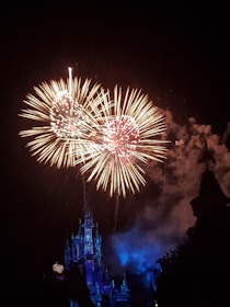 Wide shot of a colorful fireworks finale lighting up the night sky above a historic castle.