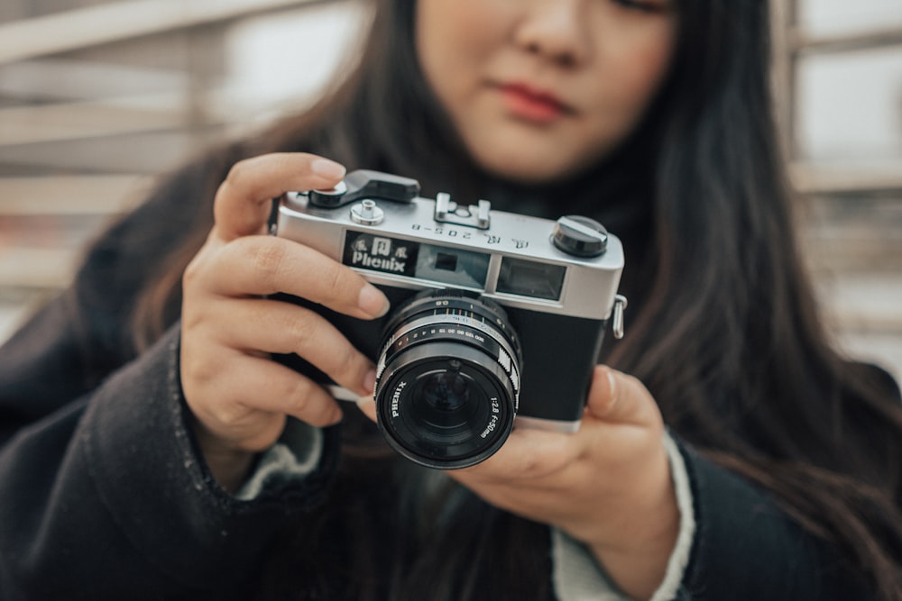 woman wearing black and gray using SLR camera