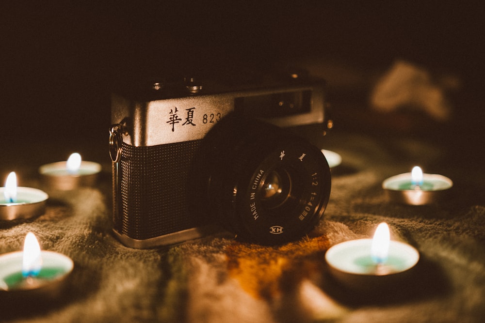 black and silver DSLR camera between tealight candles