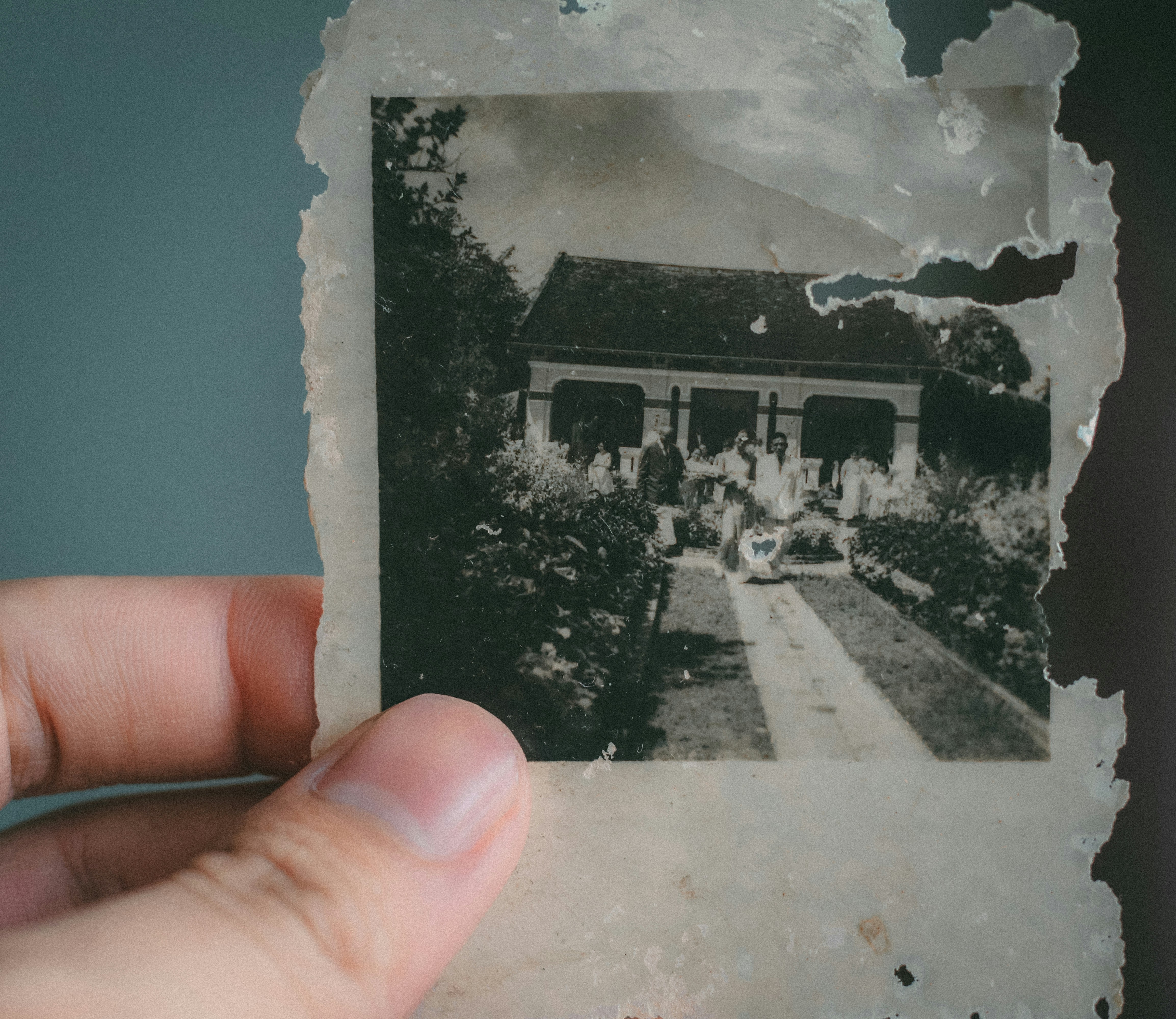 A hand holds an aged black and white family photograph.
