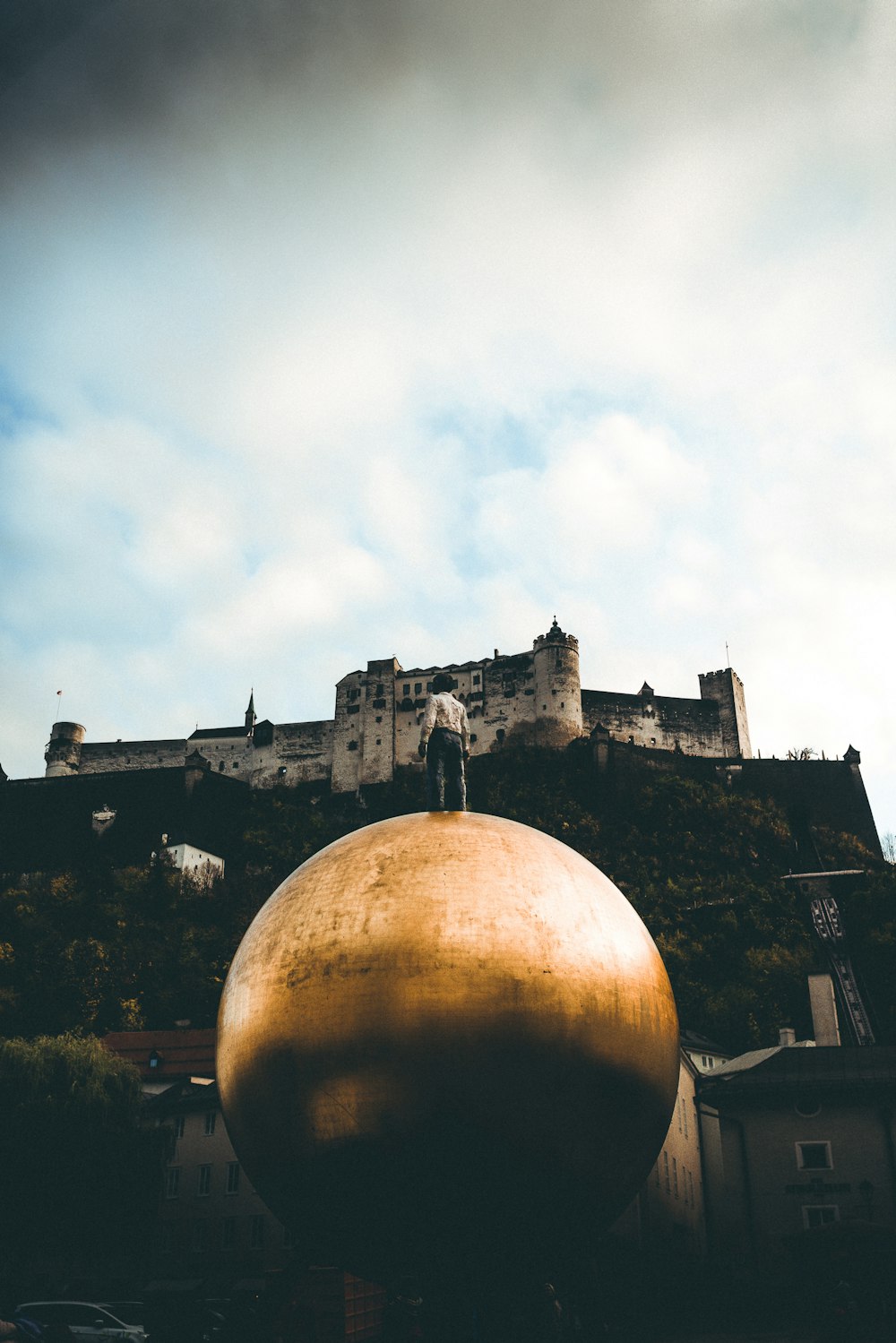 unknown person standing on gold-colored ball statue