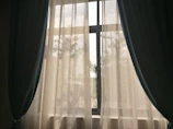 Rich velvet navy blue curtains framing a large window with a garden view.