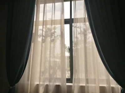 Rich velvet navy blue curtains framing a large window with a garden view.