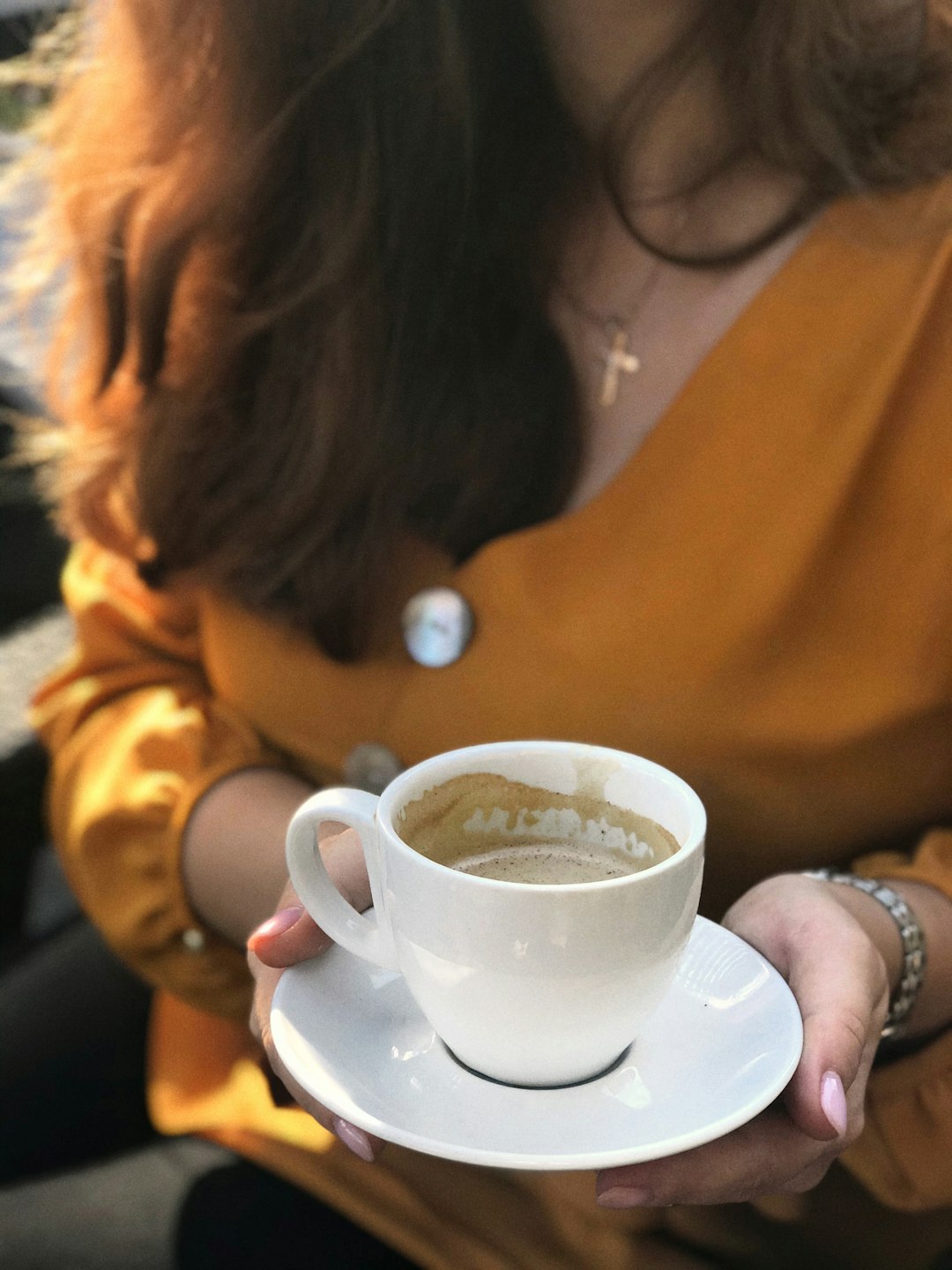 woman holding white ceramic cup on saucer