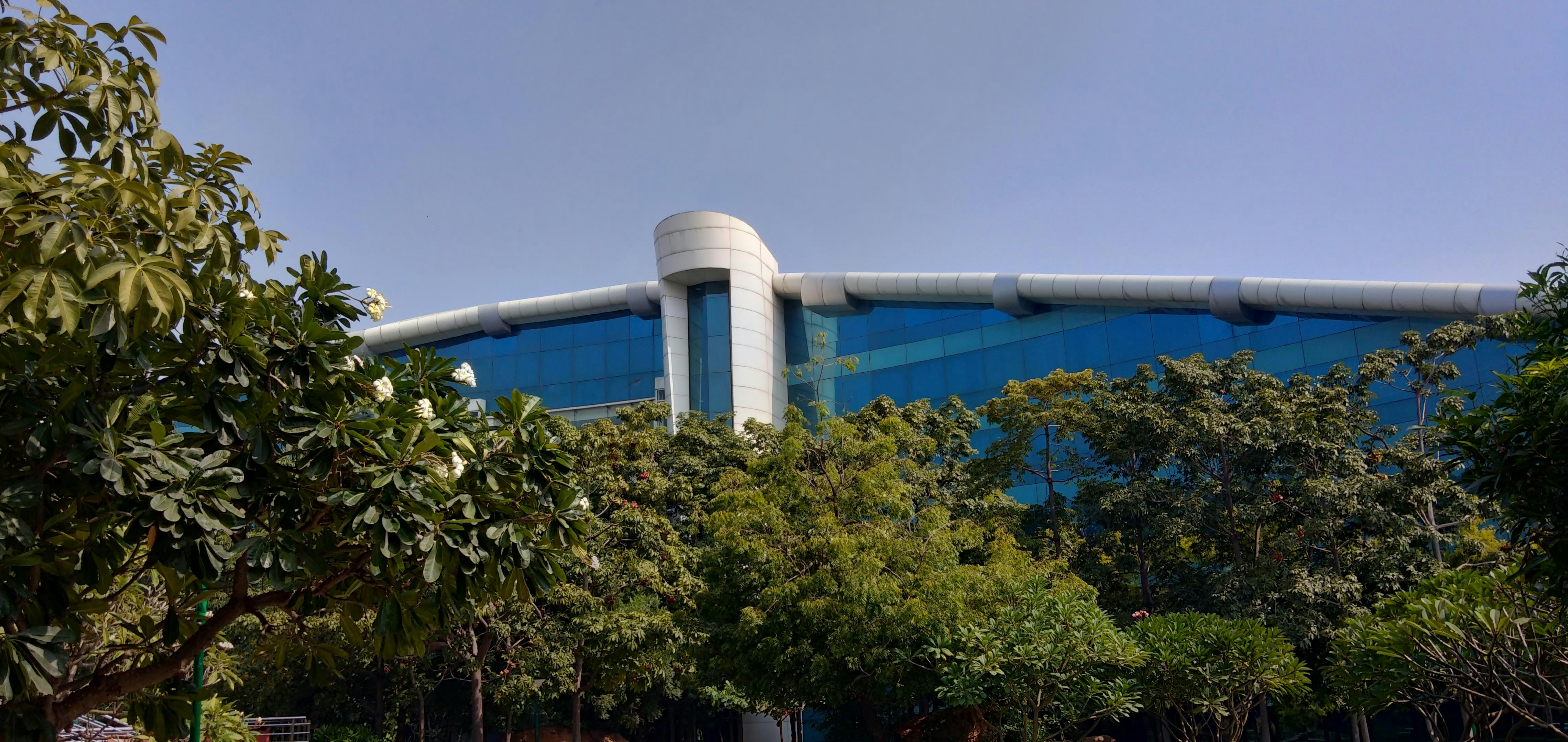 a large building with a curved roof surrounded by trees