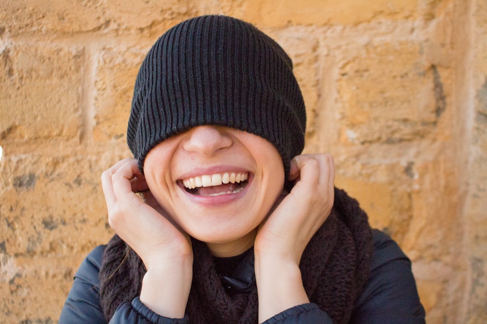 smiling woman covering her eyes with her knit cap