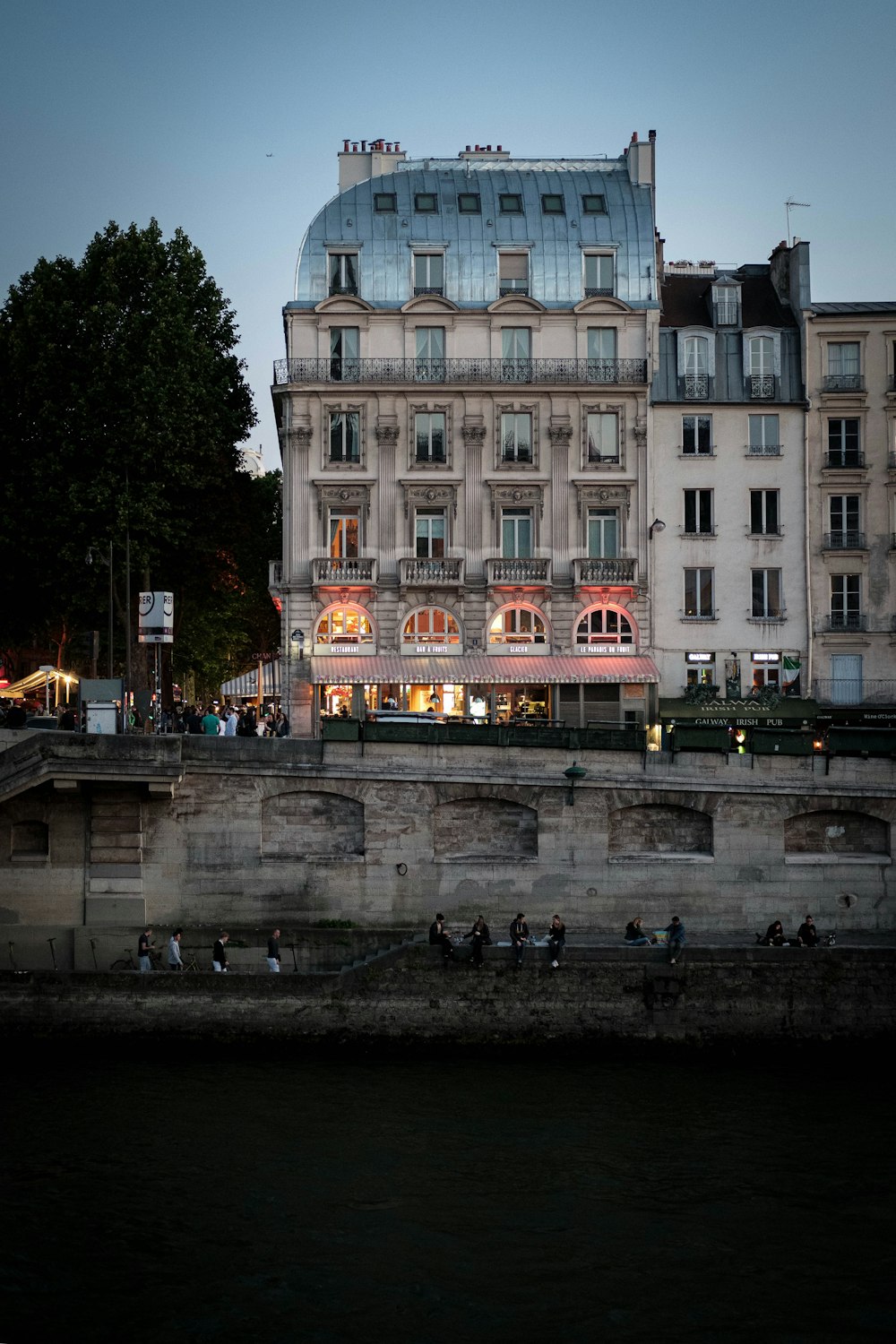 people walk beside buildings near body of water