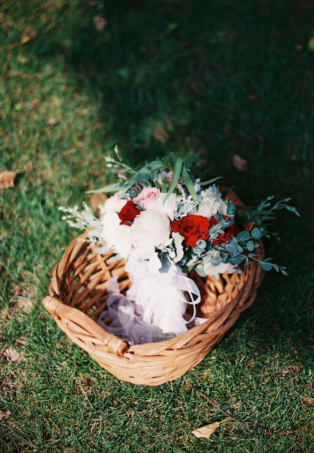 white and red flower bouquet in basket
