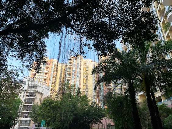 Sunlit Vida Residences tower rising above lush tropical landscaping with a glimpse of Biscayne Bay.